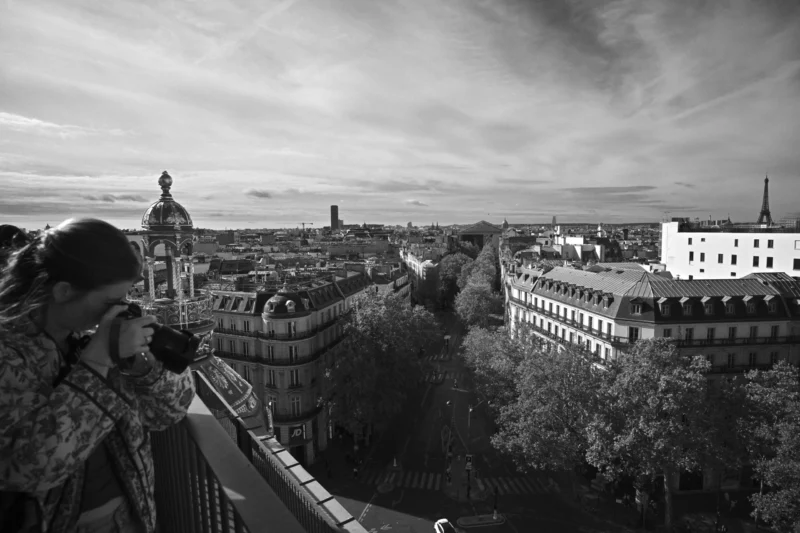 Personne prenant une photo d’un panorama urbain avec des bâtiments historiques et une cathédrale au loin sous un ciel