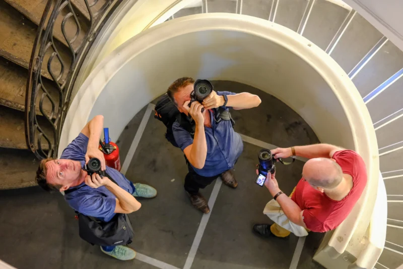 Trois personnes prenant des photos avec des appareils professionnels dans un espace architectural en arc de cercle, vue