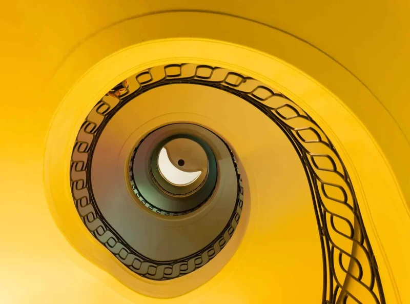Escalier en colimaçon décoré avec des motifs de pellicule de film, vue plongeante vers un centre éclairé en jaune