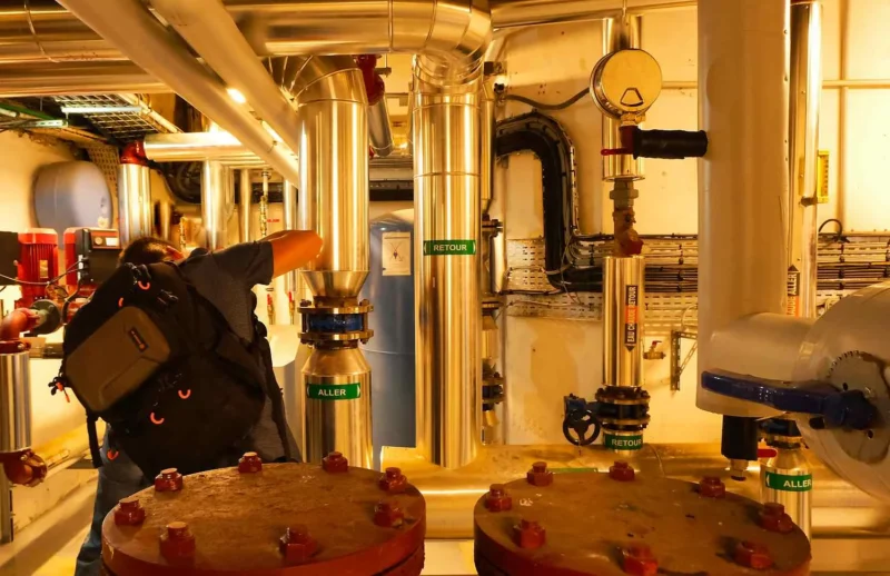 Technicien inspectant des valves et tuyauteries industrielles dans un espace équipé de systèmes de contrôle et