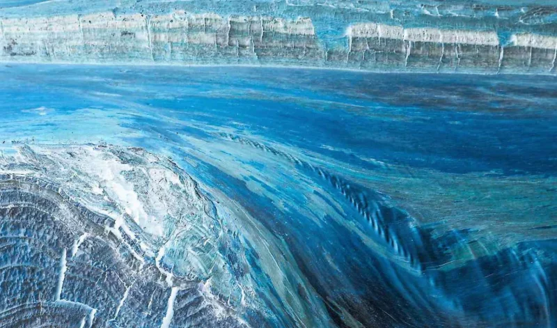 Monique · 25/09/2026 · 1500 x 883 Vue aérienne de glacier bleu aux reflets striés se jetant dans une étendue d'eau sombre, ambiance glaciale et minérale