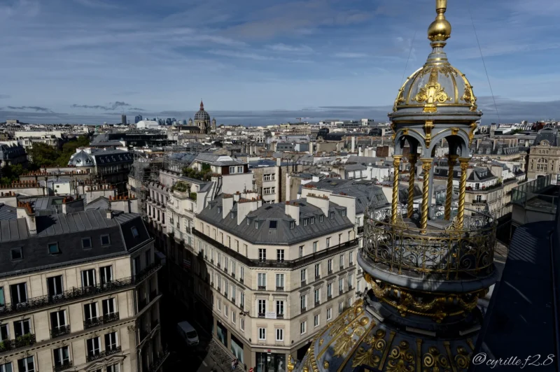Vue panoramique d’un quartier parisien avec un dôme doré en premier plan et des immeubles haussmanniens en arrière-plan