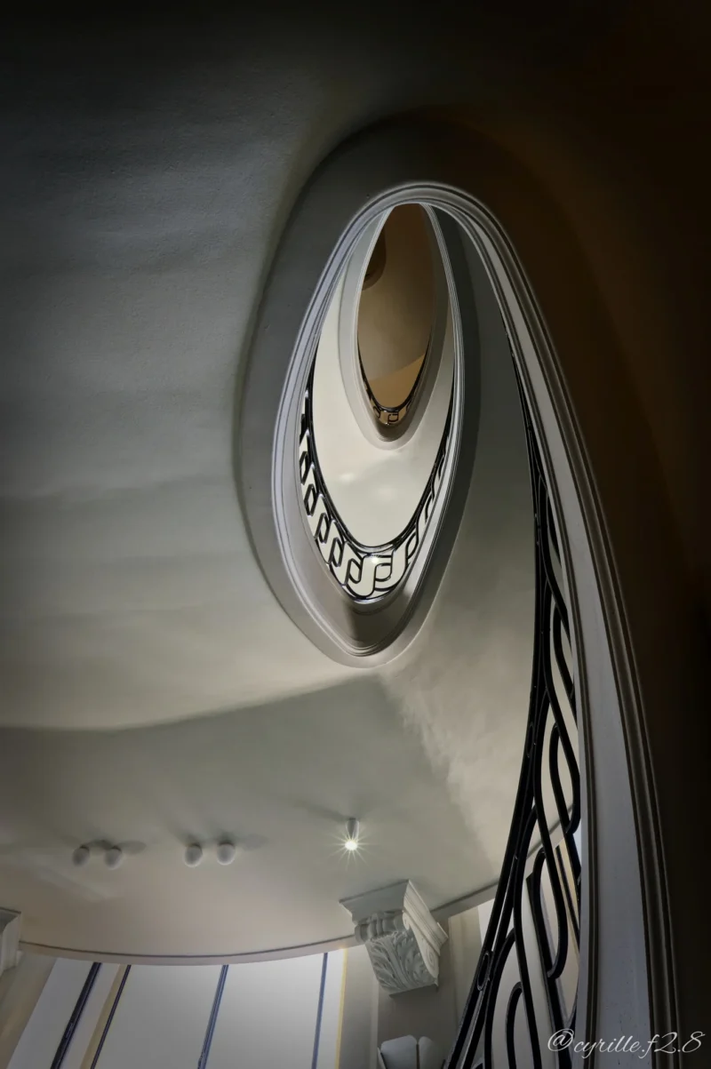 Vue plongeante d'un escalier en colimaçon élégant dans un intérieur lumineux et moderne, avec une balustrade en métal noir