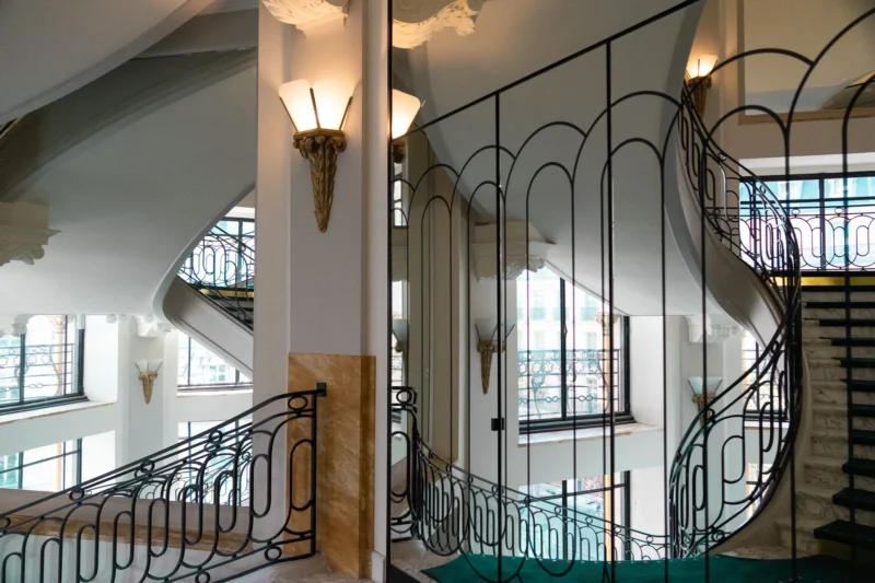 Escalier intérieur élégant avec balustrades en fer forgé et murs blancs, vue sur deux volées d'escaliers symétriques