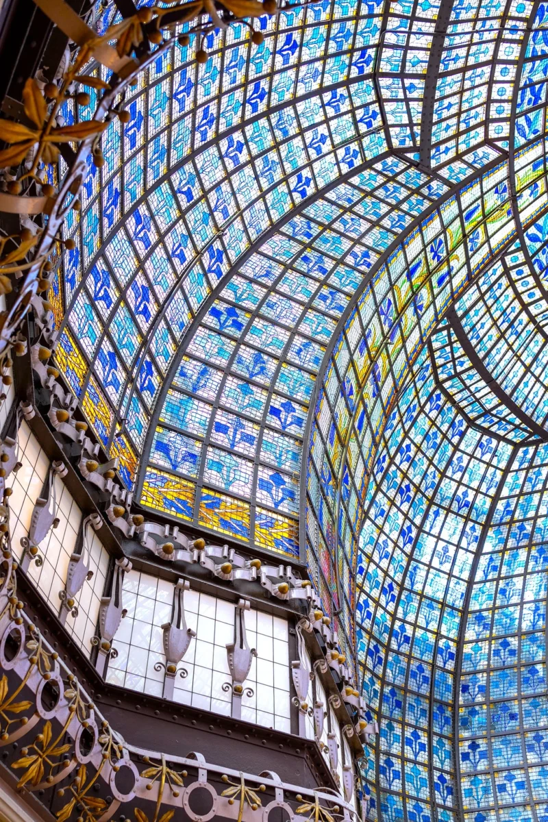 Voute intérieure ornée de vitraux colorés aux motifs géométriques et floraux, soutenue par une structure métallique
