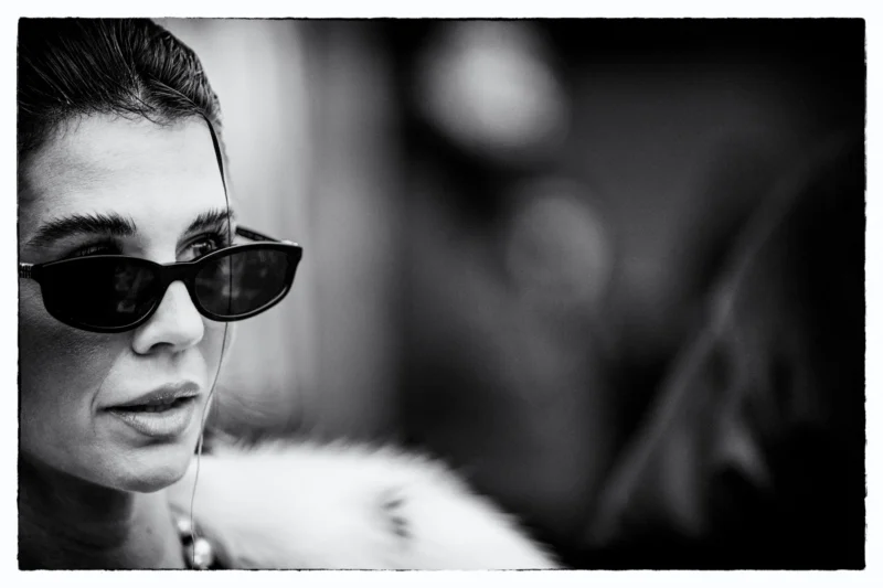 Portrait en noir et blanc d’une personne portant des lunettes et un pull, regardant vers la gauche avec une expression neutre