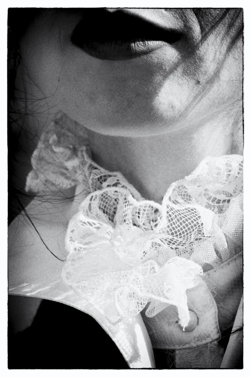 Portrait en noir et blanc d’un visage partiellement caché par une dentelle délicate et un tissu léger.