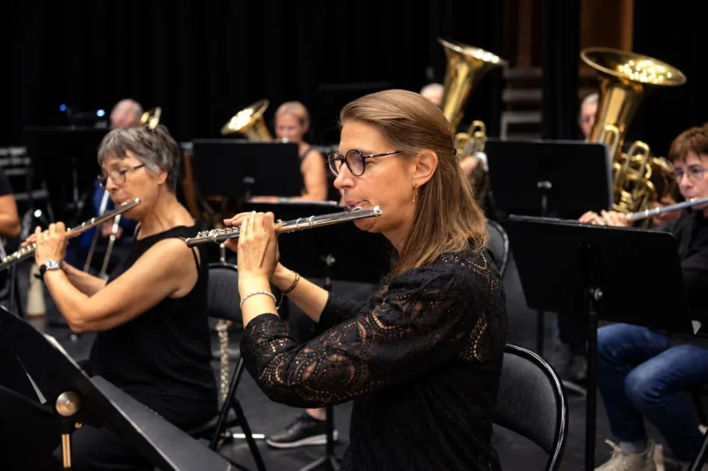 Deux musiciennes jouant du hautbois dans un orchestre, entourées d'autres instrumentistes dont des cuivres, en concert