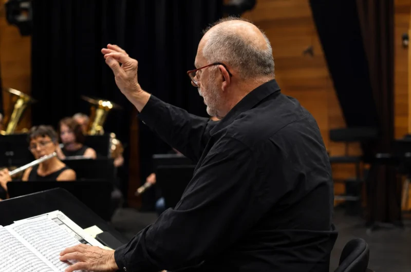 Un chef d'orchestre dirigeant une partition musicale devant un groupe de musiciens en concert, ambiance intimiste