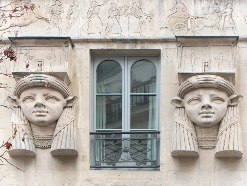Jean paul · 20/03/2023 · 2400 x 1812 Façade ornée de deux têtes sculptées style égyptien encadrant une fenêtre à double battant avec balcons en fer forgé.