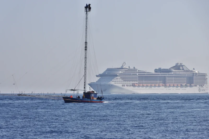 Jean paul · 06/07/2024 · 2400 x 1600 Un voilier avec des personnes en hauteur sur un mât et un paquebot en arrière-plan sur une mer calme sous un ciel dégagé