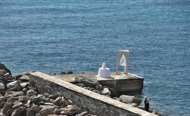 Jean paul · 18/05/2025 · 2400 x 1471 Structure en bord de mer avec une sculpture en forme de bouteille et un symbole abstrait, vue depuis une jetée rocheuse.