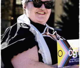 Thierry · 03/10/2026 · 1600 x 2400 Personne souriante avec des lunettes de soleil, un accessoire dans les cheveux et un drapeau coloré à motifs géométriques
