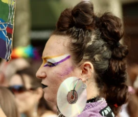 Francoise · 03/10/2026 · 2400 x 1600 Personne aux cheveux coiffés en chignon avec maquillage coloré et bijoux, participant à une fête ou événement festif