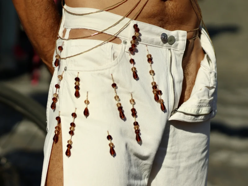Francoise · 03/10/2026 · 2400 x 1600 Personne portant un pantalon blanc orné de franges et de perles colorées, style décontracté et artistique, vue rapprochée