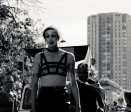 Cyrille · 03/10/2026 · 2026 x 1520 Défilé festif en noir et blanc avec participants déguisés en costumes extravagants, dont une personne centrale en tenue