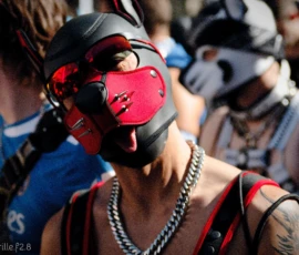 Cyrille · 03/10/2026 · 2026 x 1519 Personne portant un masque respirateur rouge et noir avec des éléments métalliques, entourée d’un collier à chaîne, dans