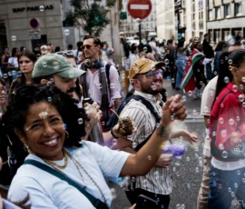 Cyrille · 03/10/2026 · 2026 x 1347 Groupe de personnes en fête sur une rue animée, lançant des bulles de savon et souriantes sous un ciel clair