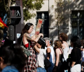 Cyrille · 03/10/2026 · 2026 x 1347 Manifestation avec une personne tenant une banderole et un appareil photo, entourée d'un groupe en mouvement dans une rue