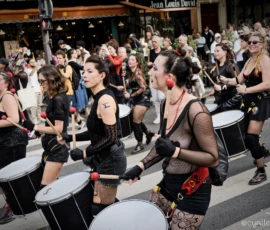 Cyrille · 03/10/2026 · 2026 x 1520 Groupe de musiciens jouant des tambours lors d'une parade festive en ville, ambiance animée et colorée