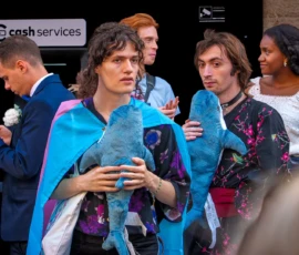 Marc · 03/10/2026 · 1692 x 1080 Groupe de personnes en tenue décontractée et élégante posant devant un distributeur de cash, dont une personne tient