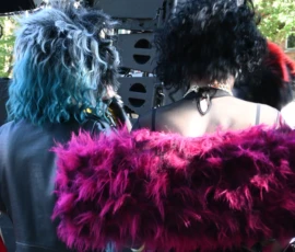 Aurélie · 2048 x 1797 Deux personnes déguisées avec perruques colorées et costumes extravagants, dont une porte une écharpe en fourrure rose vif