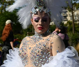 Aurélie · 1366 x 2048 Personne en costume de scène extravagant avec plumes blanches et paillettes, participant à une parade ou un défilé festif