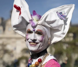 Alice · 03/10/2026 · 1920 x 2400 Personne déguisée en reine du carnaval avec coiffe blanche ornée de fleurs et accessoires colorés, souriante lors d'une fête