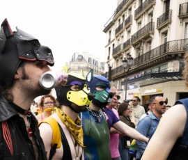 Alice · 03/10/2026 · 2400 x 1600 Groupe de personnes déguisées en masques colorés et costumes originaux dans une rue animée, participant à une manifestation