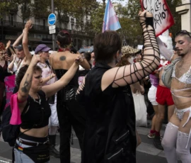 Alice · 03/10/2026 · 2400 x 1600 Manifestation festive avec participants levant les bras, certains portant des tenues colorées et des drapeaux LGBTQ+