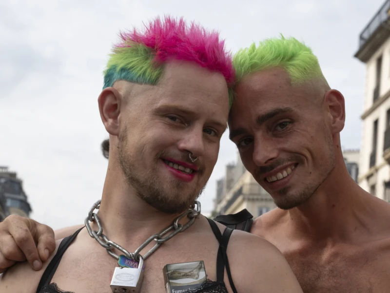 Alice · 03/10/2026 · 2400 x 1600 Deux personnes souriantes avec des coiffures colorées, l'une en tenue festive, posant ensemble en extérieur dans