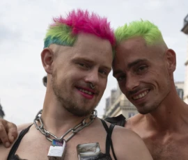 Alice · 03/10/2026 · 2400 x 1600 Deux personnes souriantes avec des coiffures colorées, l'une en tenue festive, posant ensemble en extérieur dans