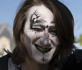 Alice · 03/10/2026 · 1920 x 2400 Personne souriante avec maquillage facial stylisé représentant des motifs de branches et d'oiseaux, vêtue d'une tenue sombre