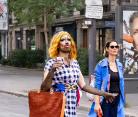 Muriel · 03/10/2026 · 2048 x 1365 Deux personnes marchant en ville, l'une habillée de manière excentrique avec une perruque blonde et des accessoires colorés