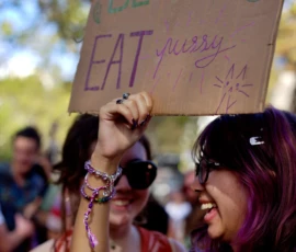Fabienne · 03/10/2026 · 1603 x 2400 Deux personnes souriantes tenant une pancarte colorée avec écrit 'BE veggie EAT quesy' lors d'un rassemblement en extérieur.