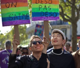 Fabienne · 03/10/2026 · 2400 x 2400 Deux personnes souriantes participant à une manifestation avec des pancartes colorées aux messages en français, entourées