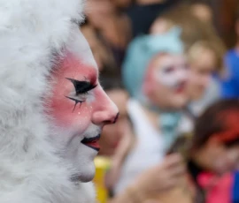 Xavier · 03/10/2026 · 1280 x 854 Personnage en costume de clown à face blanche et maquillage rouge et noir parmi une foule colorée lors d'un événement public