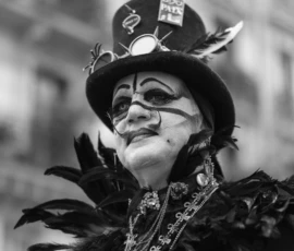 Laurence · 03/10/2026 · 1350 x 900 Personne déguisée en costume extravagant avec chapeau à plumes et maquillage facial, participant à une manifestation ou