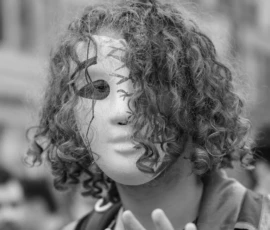 Laurence · 03/10/2026 · 1350 x 900 Personne portant un masque facial décoré de motifs géométriques et de traits noirs, en train de faire un geste avec la main