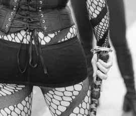 Laurence · 03/10/2026 · 1350 x 900 Personne vêtue d'une tenue corset et collants à motifs géométriques tenant un accessoire en forme de massue, ambiance