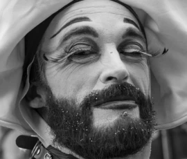 Laurence · 03/10/2026 · 1350 x 900 Portrait en noir et blanc d’une personne aux yeux fermés, vêtue d’un manteau, avec une expression calme sous une lumière